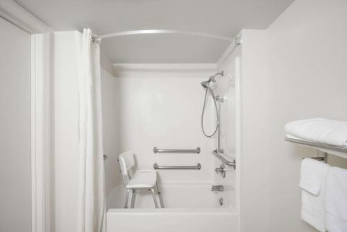 a white bathroom with a shower and a chair at Super 8 by Wyndham Dandridge in Dandridge