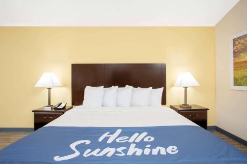a hotel room with a bed with a hello sunshine sign on it at Days Inn by Wyndham Lake City in Lake City