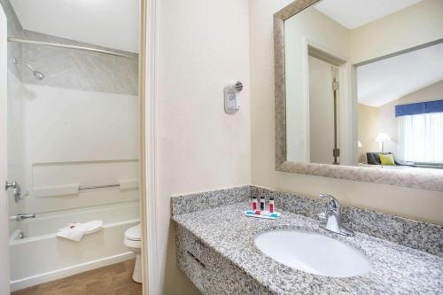 a bathroom with a sink and a toilet and a mirror at Days Inn by Wyndham Lake City in Lake City