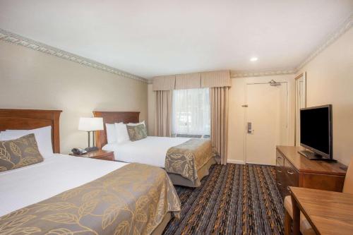 a hotel room with two beds and a flat screen tv at Days Inn by Wyndham San Diego Hotel Circle in San Diego