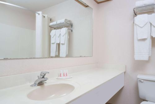 a white bathroom with a sink and a mirror at Super 8 by Wyndham Sheldon in Sheldon
