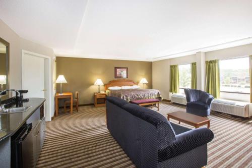 a hotel room with a bed and a living room at Super 8 by Wyndham Oxford in Oxford