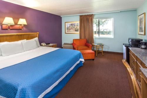 a hotel room with a bed and a chair at Days Inn by Wyndham Portage in Portage