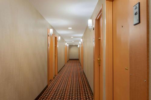 a long hallway with wooden doors and a carpet at Days Inn by Wyndham Edmonton Downtown in Edmonton