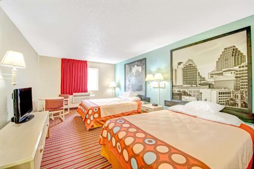 a hotel room with two beds and a flat screen tv at Super 8 by Wyndham San Antonio/Fiesta in San Antonio