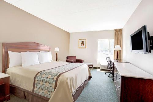 a hotel room with a bed and a flat screen tv at Days Inn by Wyndham Newport News City Center Oyster Point in Newport News
