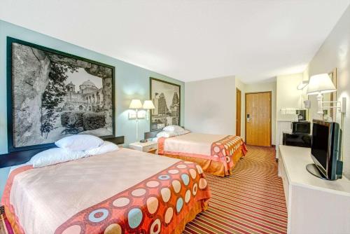 a hotel room with two beds and a flat screen tv at Super 8 by Wyndham San Antonio/Fiesta in San Antonio