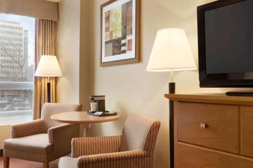 a hotel room with a tv and chairs and a table at Days Inn by Wyndham Edmonton Downtown in Edmonton