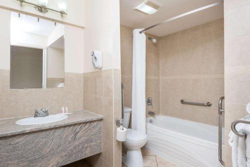 a bathroom with a sink and a tub and a toilet at Super 8 by Wyndham Cambridge/Kitchener/Waterloo Area in Cambridge