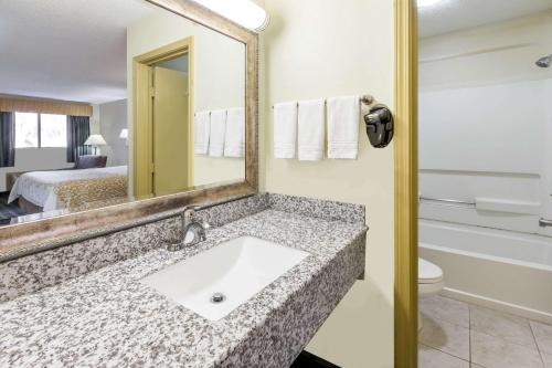 baño con lavabo, espejo y cama en Days Inn by Wyndham Kent - Akron, en Kent