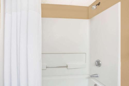 a bathroom with a shower with a white shower curtain at Days Inn by Wyndham Newport News City Center Oyster Point in Newport News