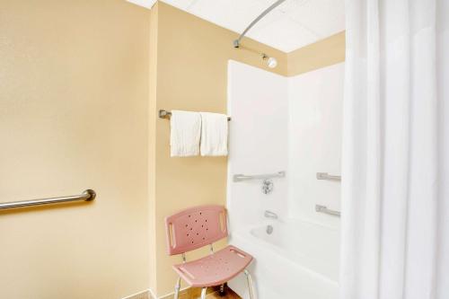 a pink chair in a bathroom with a shower at Days Inn by Wyndham Newport News City Center Oyster Point in Newport News