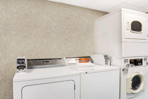 a white laundry room with a washer and dryer at Days Inn by Wyndham Newport News City Center Oyster Point in Newport News