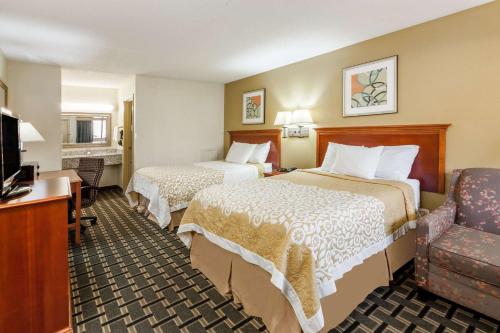 a hotel room with two beds and a chair at Days Inn by Wyndham Kent - Akron in Kent