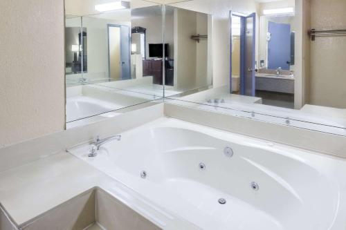 a bathroom with a large white tub with a large mirror at Days Inn by Wyndham Walterboro in Walterboro