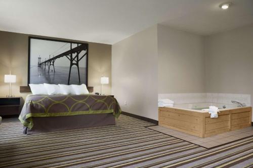 a hotel room with a bed and a bath tub at Super 8 by Wyndham Manistee in Manistee