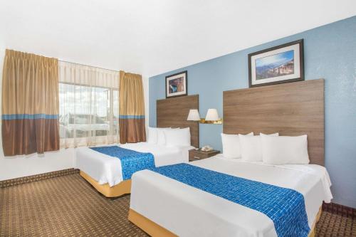 a hotel room with two beds and a window at Travelodge by Wyndham Williams Grand Canyon in Williams
