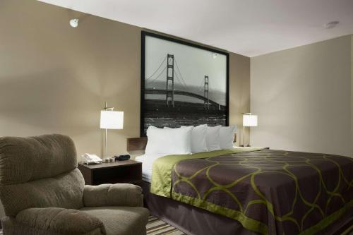 a hotel room with a bed with a large picture of a bridge at Super 8 by Wyndham Manistee in Manistee
