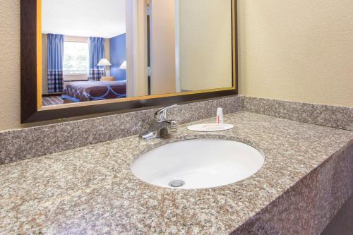 a bathroom counter with a sink and a mirror at Super 8 by Wyndham Dothan in Dothan