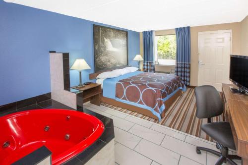 a hotel room with a bed and a red bath tub at Super 8 by Wyndham Dothan in Dothan