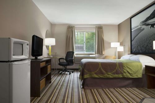 a hotel room with a bed and a television at Super 8 by Wyndham Manistee in Manistee