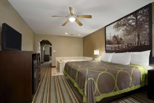a hotel room with a bed and a ceiling fan at Super 8 by Wyndham Tupelo Airport in Tupelo
