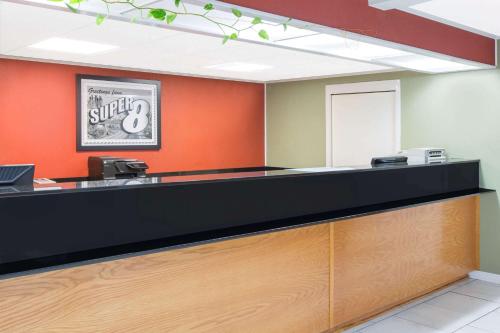 an empty waiting room with an orange wall at Super 8 by Wyndham Dothan in Dothan