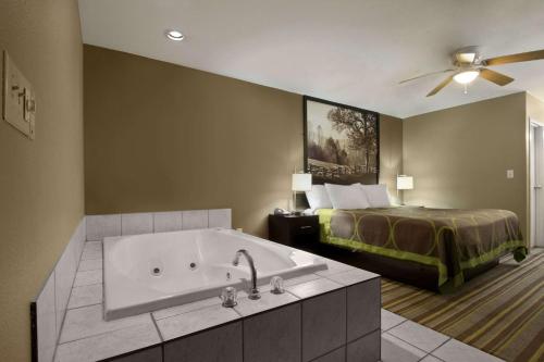 a hotel room with a tub and a bed at Super 8 by Wyndham Tupelo Airport in Tupelo