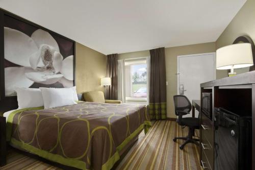a hotel room with a bed and a television at Super 8 by Wyndham Tupelo Airport in Tupelo