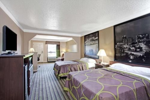 a hotel room with two beds and a flat screen tv at Super 8 by Wyndham Knoxville East in Knoxville
