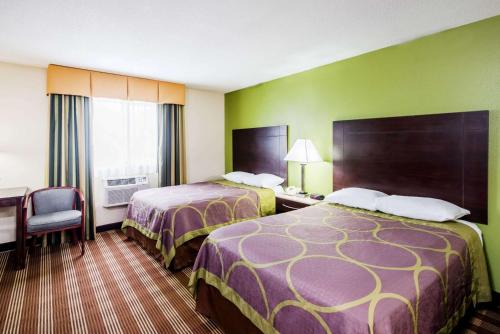 a hotel room with two beds and a desk at Super 8 by Wyndham Bangor in Bangor