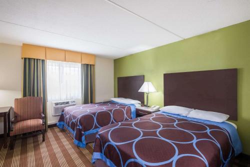 a hotel room with two beds and a chair at Super 8 by Wyndham Bangor in Bangor