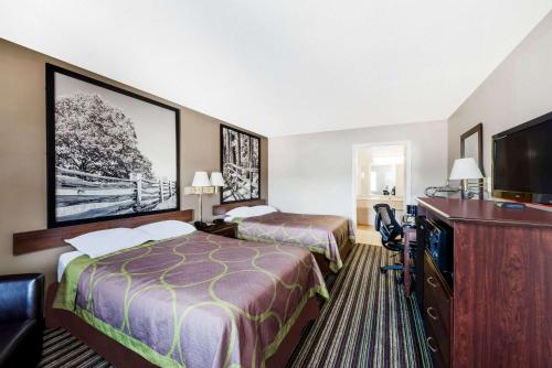 a hotel room with two beds and a flat screen tv at Super 8 by Wyndham Chattanooga Ooltewah in Ooltewah