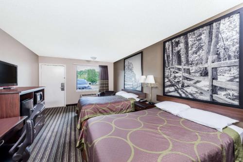 a hotel room with two beds and a flat screen tv at Super 8 by Wyndham Chattanooga Ooltewah in Ooltewah