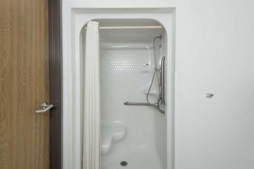 y baño con ducha y cortina de ducha. en Super 8 by Wyndham Coshocton Roscoe Village, en Coshocton