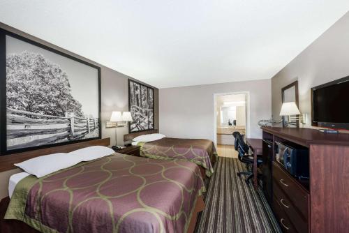 a hotel room with two beds and a flat screen tv at Super 8 by Wyndham Chattanooga Ooltewah in Ooltewah