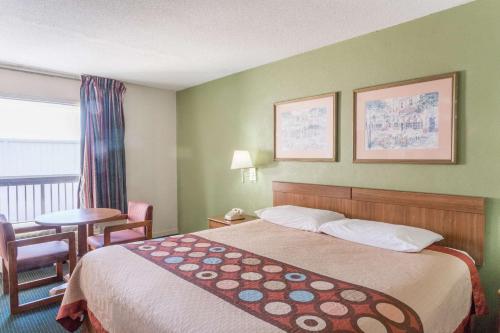 a hotel room with a bed and a table and a window at Super 8 by Wyndham Tifton in Tifton