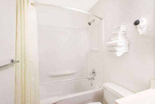 uma casa de banho branca com um chuveiro e um WC. em Super 8 by Wyndham Webster/Rochester em Webster