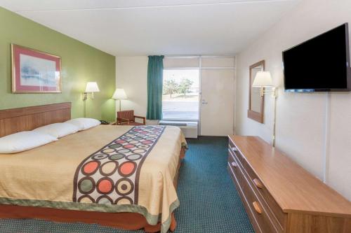 a hotel room with a large bed and a flat screen tv at Super 8 by Wyndham Tifton in Tifton