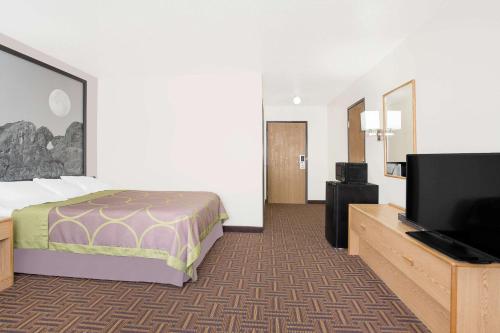 Una habitación de hotel con una cama y un televisor de pantalla plana. en Super 8 by Wyndham Bloomfield, en Bloomfield