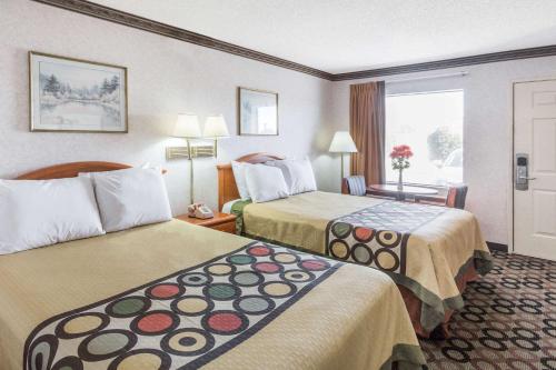 ein Hotelzimmer mit zwei Betten und einem Fenster in der Unterkunft Super 8 by Wyndham Ashburn in Ashburn
