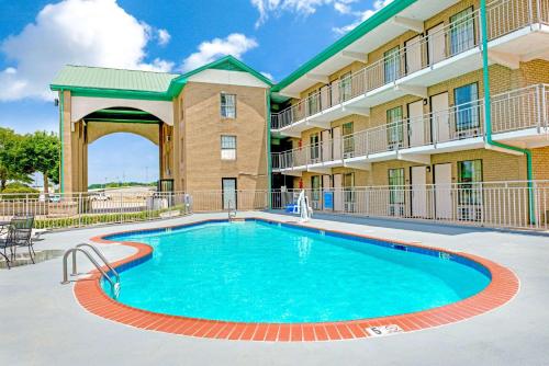 a swimming pool in front of a hotel with a building at Super 8 by Wyndham Lakeland in Lakeland
