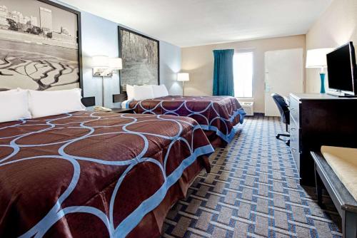 a hotel room with two beds and a flat screen tv at Super 8 by Wyndham Lakeland in Lakeland