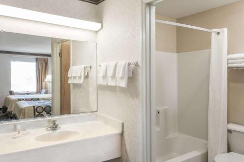 La salle de bains est pourvue d'un lavabo, d'une douche et d'un miroir. dans l'établissement Super 8 by Wyndham Ashburn, à Ashburn