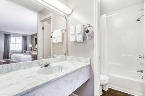 Un baño blanco con lavabo, bañera e inodoro. en Super 8 by Wyndham Madison, en Madison