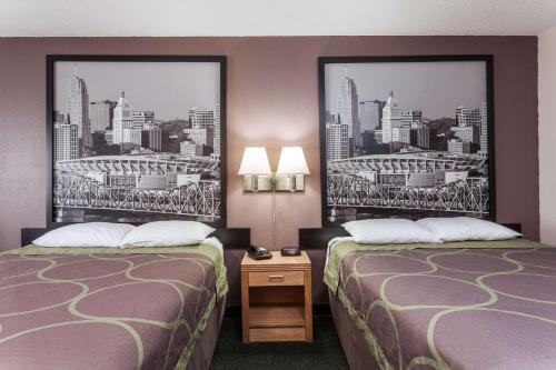 two beds in a hotel room with posters on the wall at Super 8 by Wyndham Carrollton in Carrollton