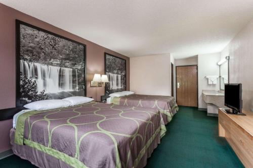 a hotel room with two beds and a television at Super 8 by Wyndham Carrollton in Carrollton