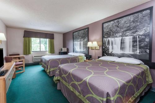 a hotel room with two beds and a television at Super 8 by Wyndham Carrollton in Carrollton