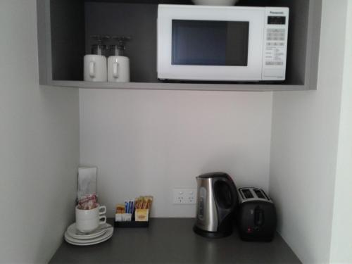 a kitchen with a microwave and a cupboard at Royal Motel Miles in Miles