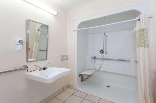 a white bathroom with a sink and a shower at Syracuse Inn in East Syracuse